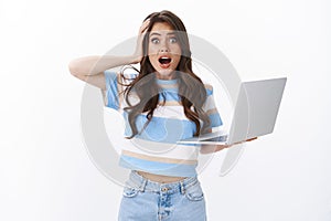 Shocked worried young female office assistant delete important document making mistake, grab head, gasping drop jaw photo