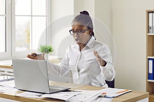 Shocked worried young woman looking at laptop computer screen