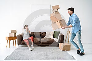 Shocked young adult man dropping cardboard boxes, looking how package fall