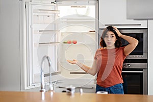 Shocked Young Arab Woman Near Empty Fridge With No Food At Home