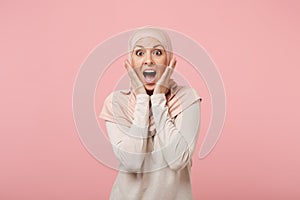 Shocked young arabian muslim woman in hijab light clothes posing isolated on pink background. People religious Islam