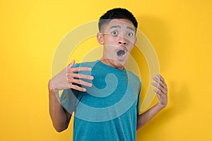 A shocked young asian man wearing a casual shirt and looking very emotional and surprised