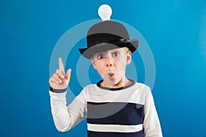 Shocked young boy in hat with lightbulb having idea