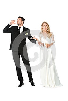 shocked young bride looking at camera while groom drinking champagne