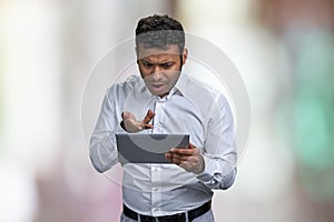 Shocked young businessman looking at digital tablet pc.