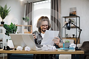 Shocked young caucasian man sitting at table with modern laptop at home office