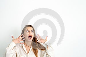 Shocked young caucasian woman with open mouth looking up and expresses surprise isolated over white background