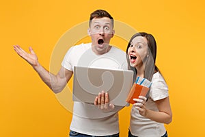 Shocked young couple two friends in white t-shirts posing isolated on yellow orange background. People lifestyle concept