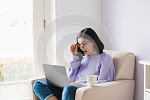 Shocked young ethnicity woman looking in computer and fixing her glasses. Lockdown news, online shocking low price