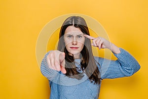 Shocked young female showing stupid gesture and pointing to camera, accusing crazy cuckoo mind, blaming insane idea, reckless plan