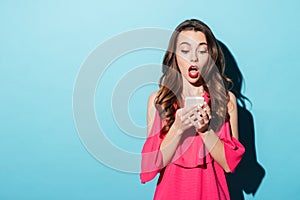 Shocked young girl in dress looking at mobile phone