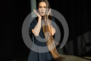 Shocked young girl with long straight hair in black dress