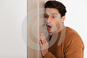 Shocked young guy listening through the door