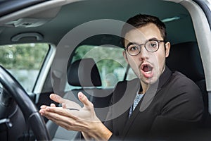 Shocked young guy is lokking at the camera. He is holding the keys in his hands. His mouth is wide open