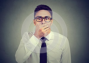 Shocked young man covering his mouth with hand