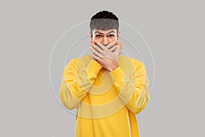 Shocked young man covering his mouth with hands