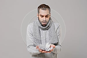 Shocked young man in gray sweater, scarf isolated on grey background. Healthy lifestyle, ill sick disease treatment