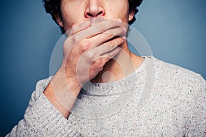 Shocked young man with his hand on his mouth