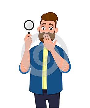 Shocked young man holding/showing magnifying glass and covering hand on mouth. Search, find, discovery, analyze, inspect.