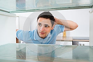 Shocked Man Looking Into Empty Refrigerator