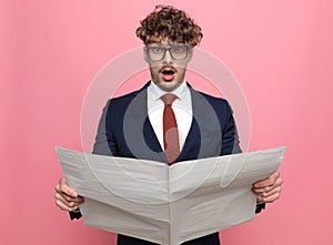 Shocked young man in suit reading newspaper