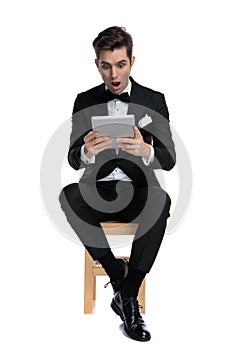 Shocked young modern man holding tab