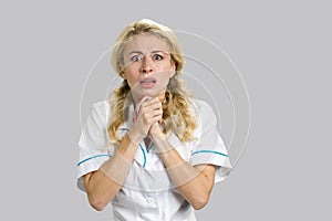 Shocked young nurse clasped hands.