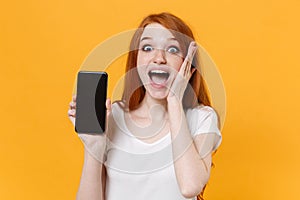 Shocked young redhead woman girl in white t-shirt posing isolated on yellow wall background. People lifestyle concept