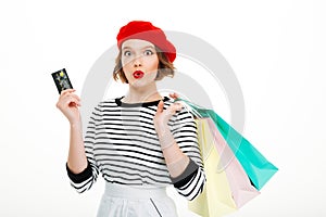 Shocked young woman holding credit card and shopping bags