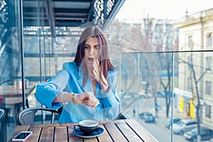 Shocked young woman holding hand with wrist watch