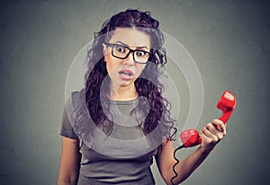 Shocked young woman looking in disbelief holding telephone handset photo