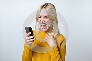 Shocked Young Woman Looking at her Mobile Phone