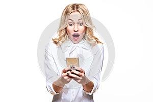 Shocked young woman looking at her mobile phone, screaming in disbelief. Woman staring at shocking text message on her phone.