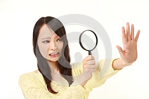 Shocked young woman looking through a magnifying glass her nails