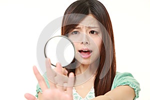 Shocked young woman looking through a magnifying glass her nails