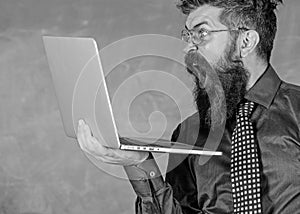 Shocking information. Hipster teacher wear eyeglasses and necktie holds laptop surfing internet. Teacher bearded shocked