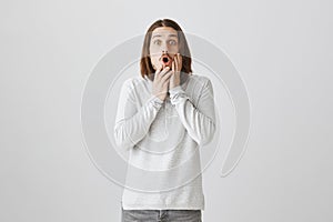 Shocking revelation been made. Studio shot of emotive surprised attractive guy with long brown hair and beard saying wow