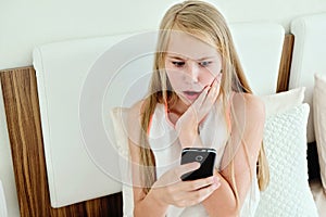 Shocking Teenage Girl Lying On Bed Using A Mobile Phone