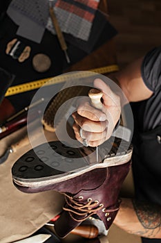 Close up of shoe maker hands producing boots in his leather workshop