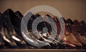 Shoe collection of black and brown leather on shelf. Mens shoes on display in shop. Footwear fashion and style. Shopping