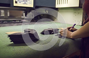 Shoe factory worker making design for new footwear standing at table with cut out details