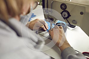 Shoe factory worker using an industrial sewing machine to make a detail for new footwear