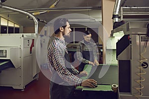 Shoe factory workers working with a cutting machine at a footwear manufacturing workshop