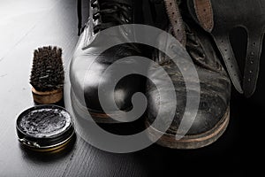 Shoe polish, brush and black military boots. Polishing and cleaning shoes on a black table