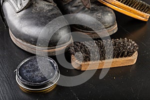 Shoe polish, brush and black military boots. Polishing and cleaning shoes on a black table