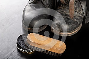 Shoe polish, brush and black military boots. Polishing and cleaning shoes on a black table