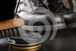 Shoe polish, brush and black military boots. Polishing and cleaning shoes on a black table