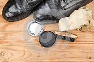 Shoe polish with brush, cloth and worn boots on wooden platform