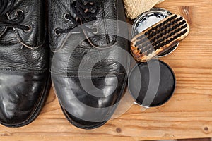 Shoe polish with brush, cloth and worn boots on wooden platform