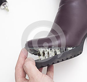 A shoe repairman glues the sole of a women s winter boot. Low-quality shoes concept, boots repair, close-up